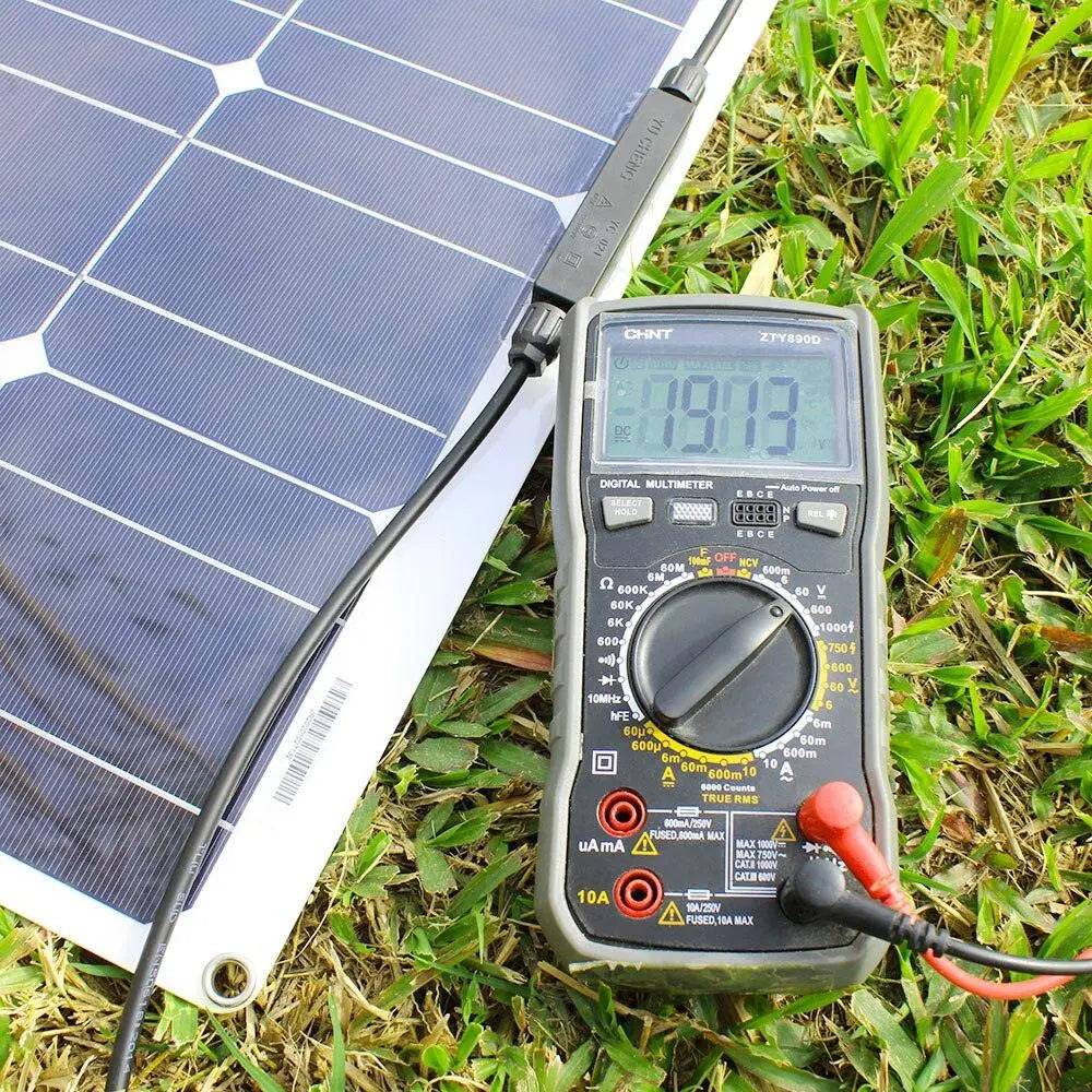 a solar panel laying on the ground next to a thermometer